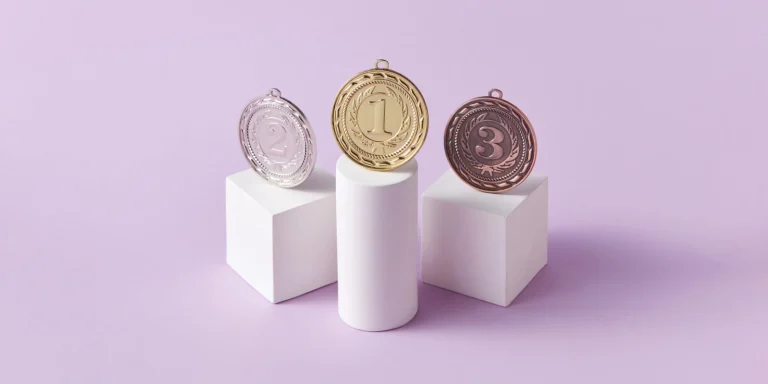 Marketing consistency helps businesses become category leaders, as seen in this image of three medals, with first place sitting on a tall column.